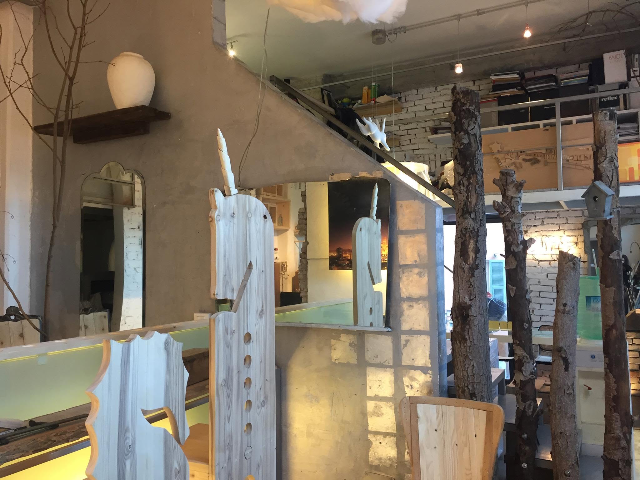 La sala con i tronchi a vista, specchi e tavoli in rovere